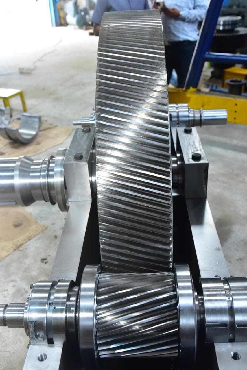Double-helical bull gear standing on its shaft above the mating pinion